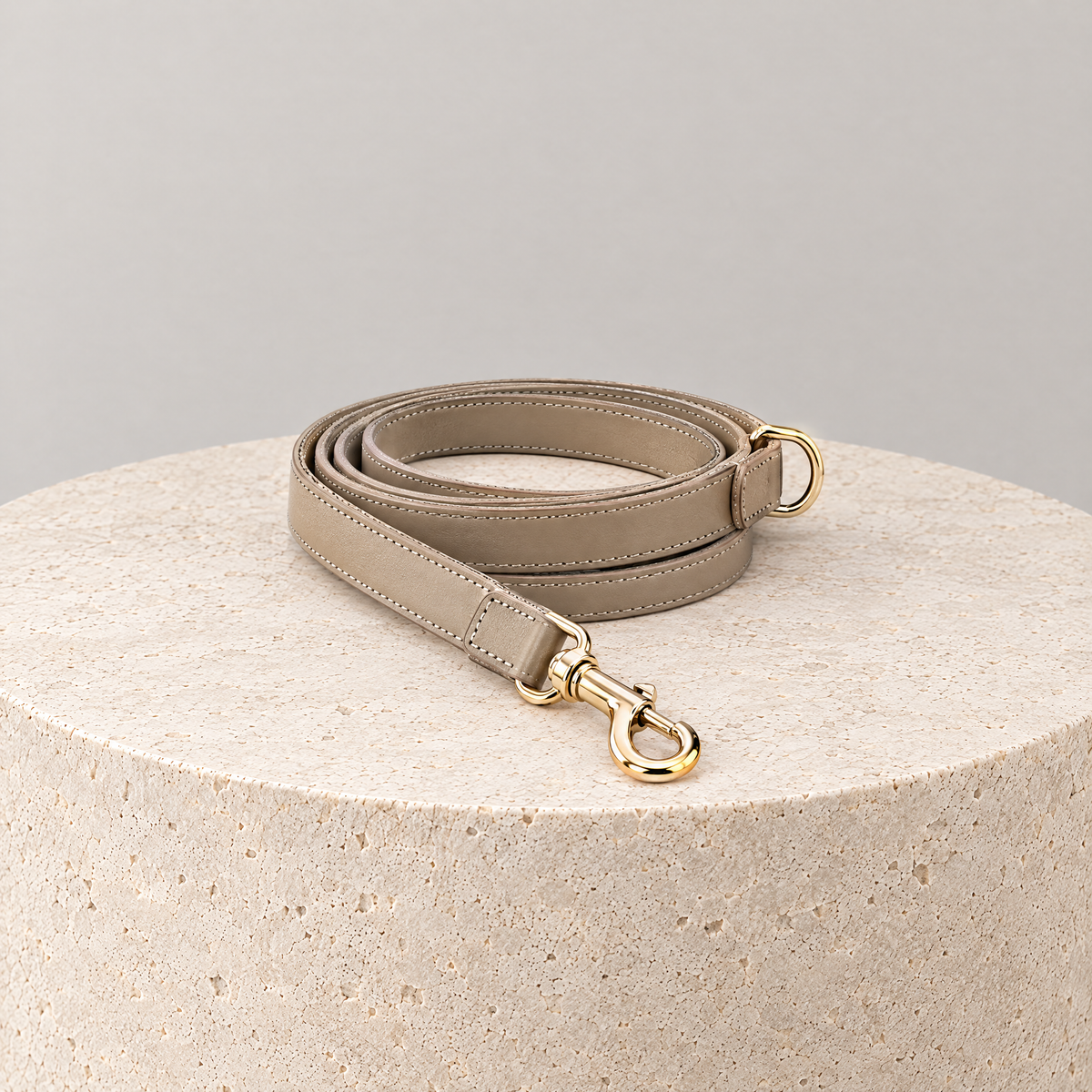 ALECOO Hundeleine Classy aus Glattleder in Taupe mit Gold auf einem runden Travertinsockel